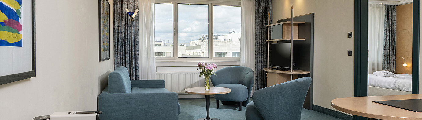 Helle Suite mit Sitzgruppe, großem Fenster und Kaffeemaschine im Maritim proArte Hotel Berlin