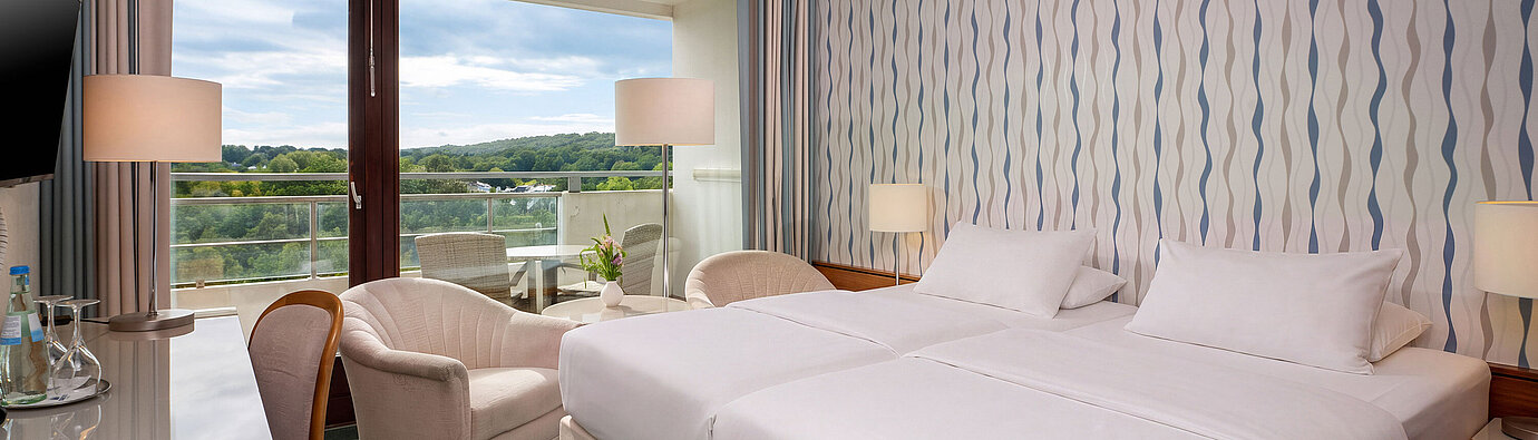 Classic Zimmer Classic Zimmer mit Doppelbett, Schreibtisch, Sessel und großem Fenster mit Blick ins Grüne