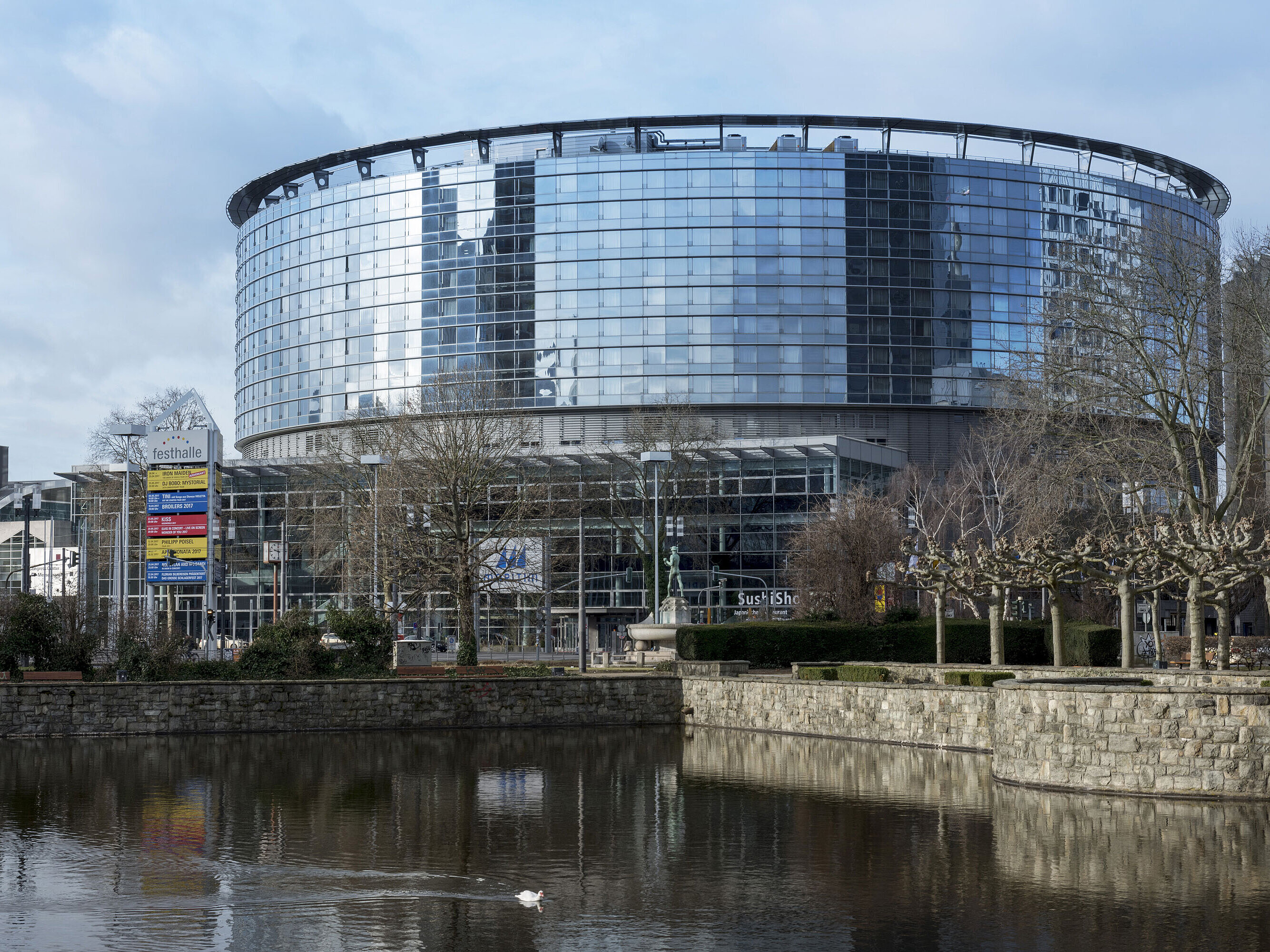 Außenansicht des Maritim Hotel Frankfurt mit moderner Glasfassade und angrenzendem Teich bei Tageslicht.