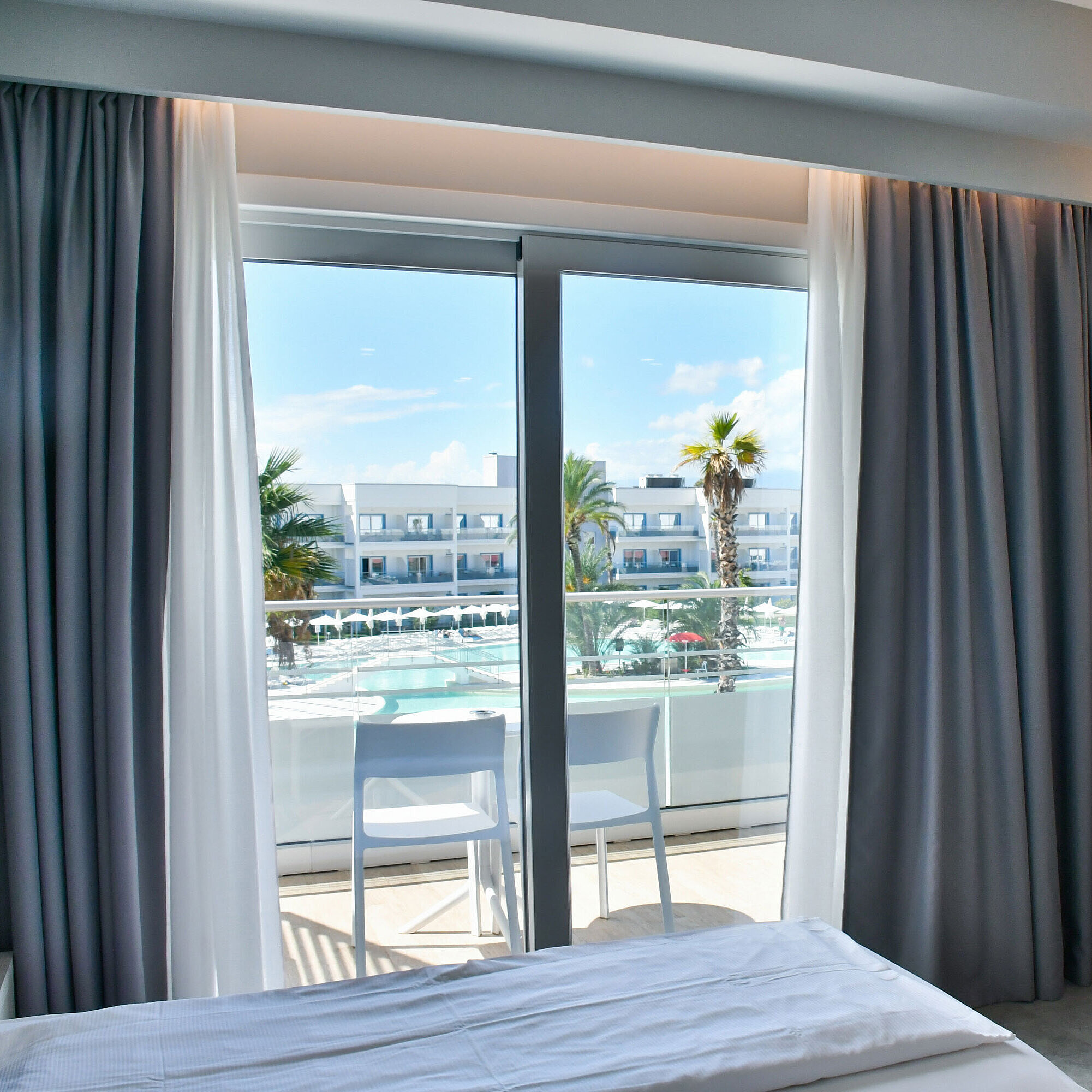 Modernes Hotelzimmer mit Balkon und direktem Blick auf den Pool im Maritim Resort Calabria