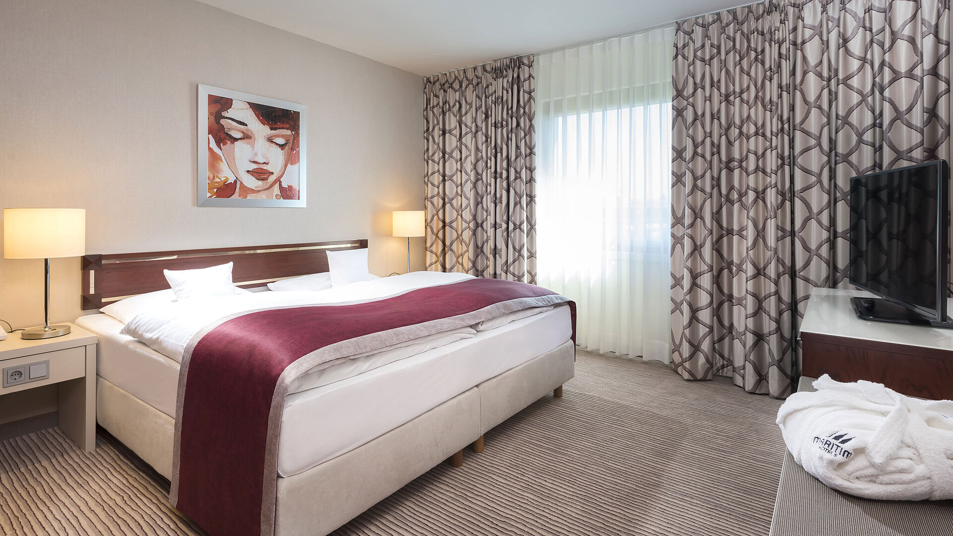 Geräumige Suite im Maritim Hotel Bonn mit gemütlichem Doppelbett, moderner Einrichtung und weinrotem Bettläufer.