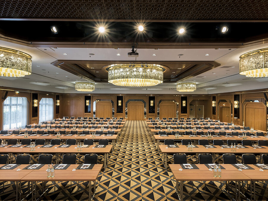 Eleganter Tagungssaal mit Bühne, Kronleuchtern und moderner Bestuhlung im Maritim Hotel Königswinter.
