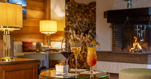 Wein, Bier und Cocktail auf Tisch vor gemütlichem Kamin in der Bar des Maritim Hotel Titisee