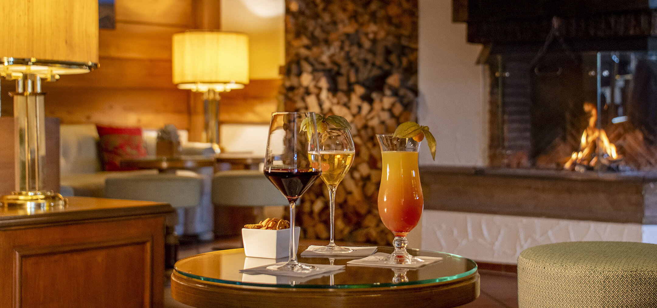 Wein, Bier und Cocktail auf Tisch vor gemütlichem Kamin in der Bar des Maritim Hotel Titisee