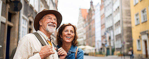 Lächelndes älteres Paar erkundet gemeinsam eine historische Altstadtstraße