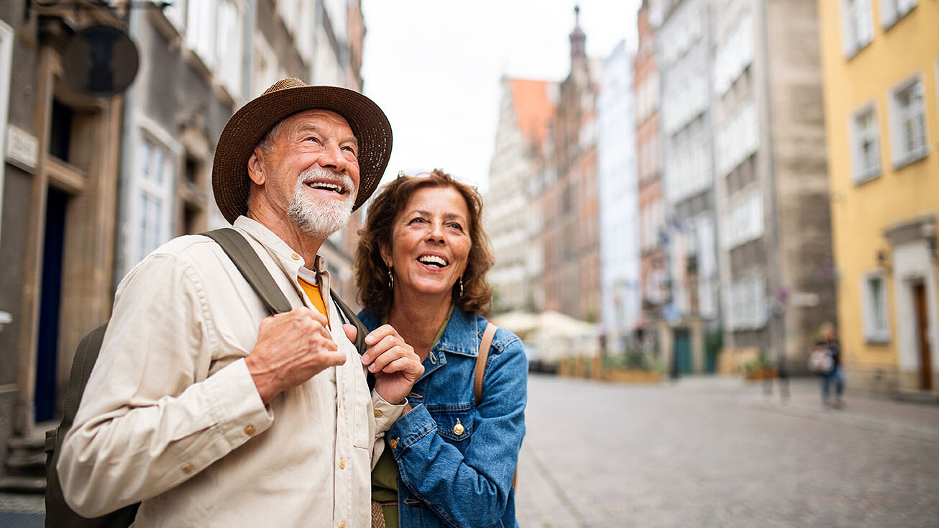 Lächelndes älteres Paar erkundet gemeinsam eine historische Altstadtstraße