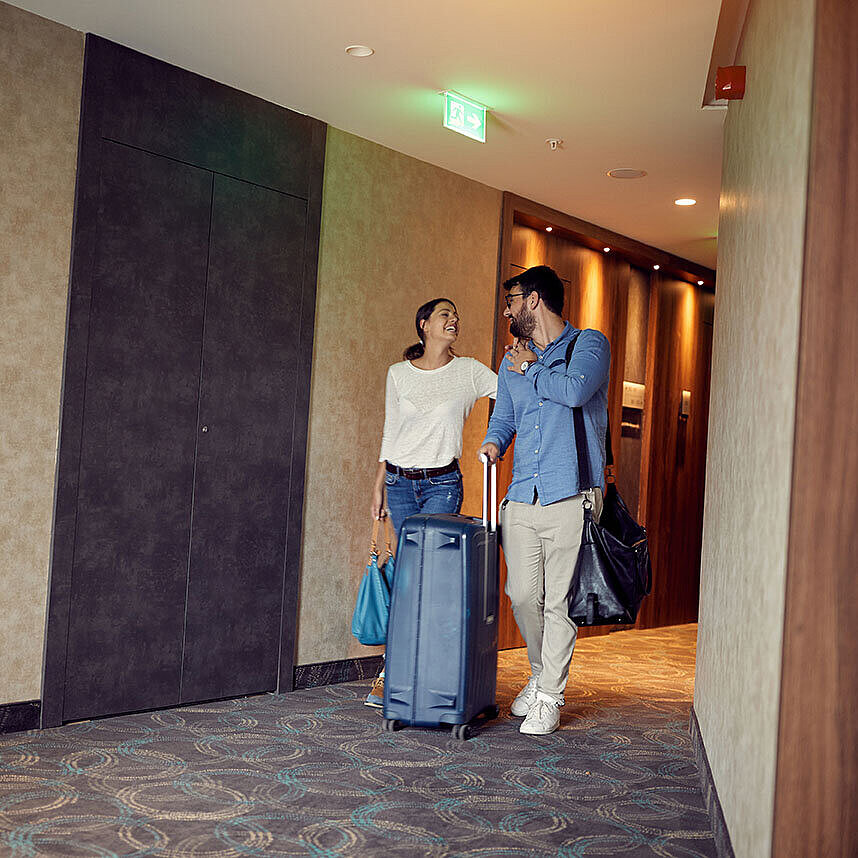 Paar mit Koffern im Hotelflur freut sich auf den Aufenthalt im Maritim Hotel