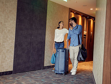 Paar mit Koffern im Hotelflur freut sich auf den Aufenthalt im Maritim Hotel