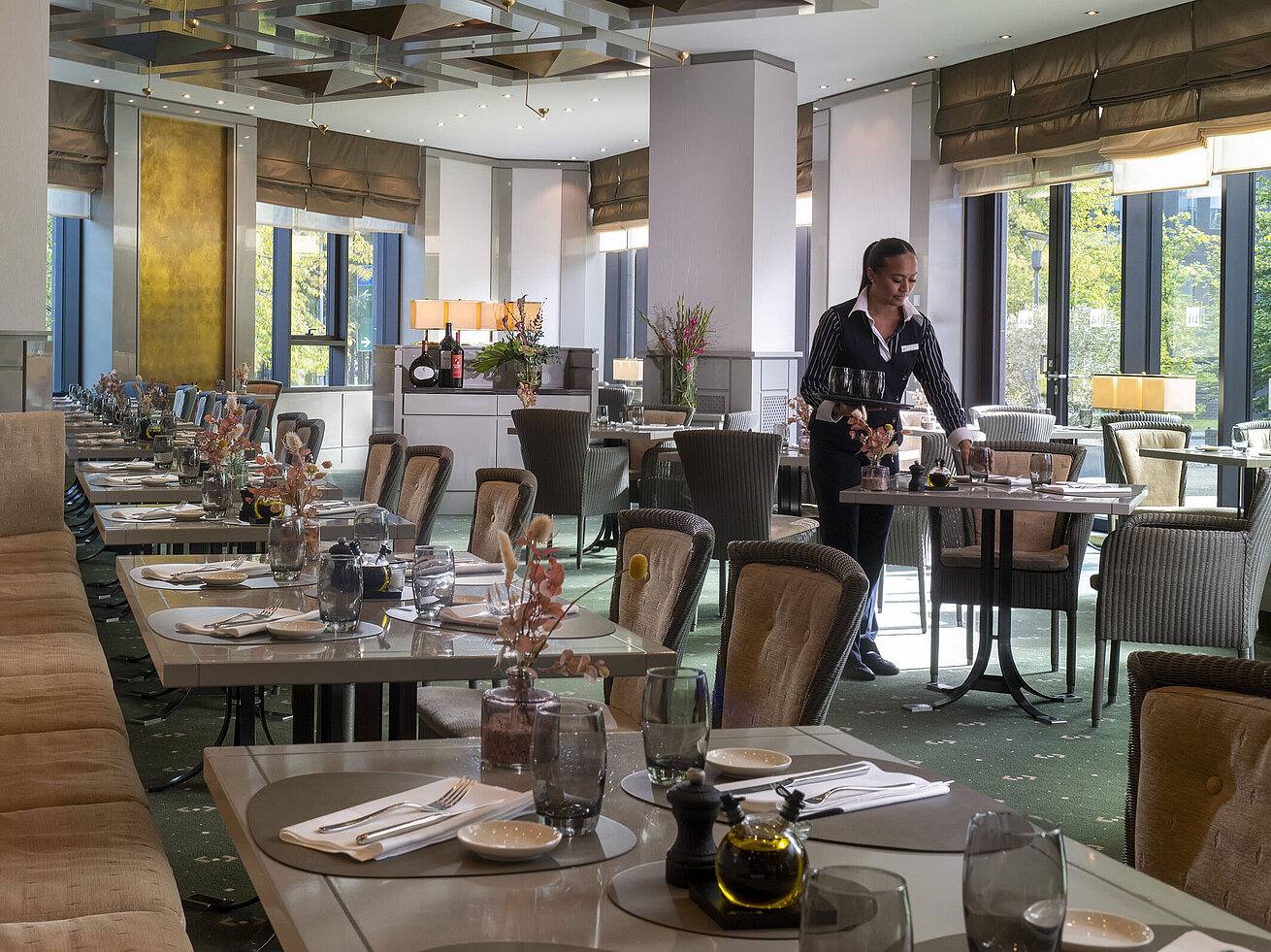 Stilvoll eingerichtetes Restaurant im Maritim Hotel Düsseldorf mit gedeckten Tischen und einer Servicemitarbeiterin.