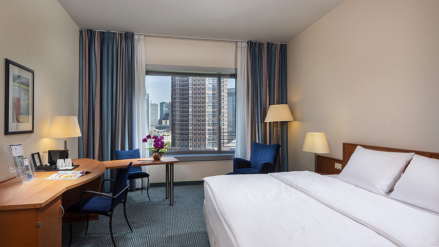 Superior Zimmer im Maritim Hotel Frankfurt mit Doppelbett, Schreibtisch und Blick auf die Frankfurter Skyline.