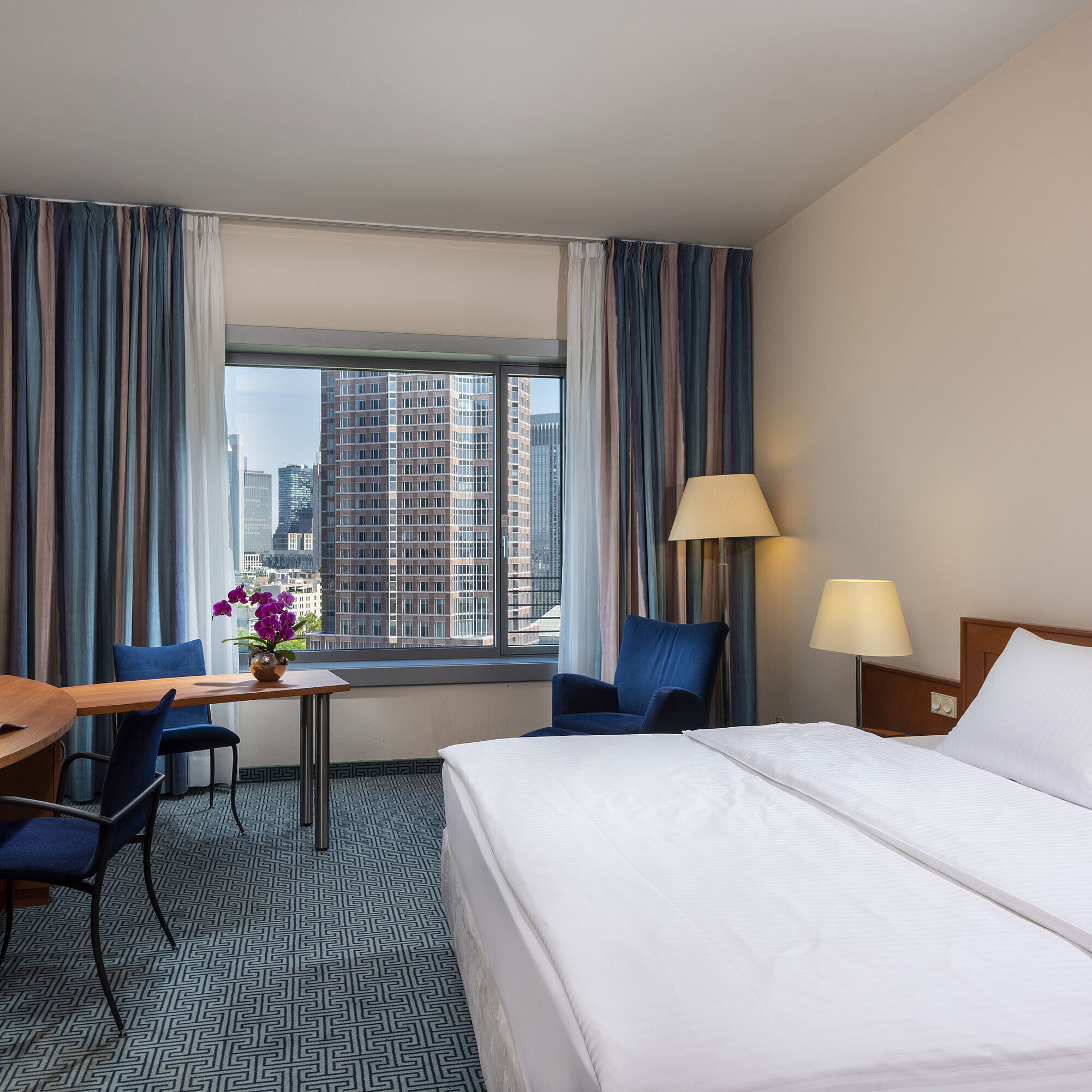 Superior Zimmer im Maritim Hotel Frankfurt mit Doppelbett, Schreibtisch und Blick auf die Frankfurter Skyline.