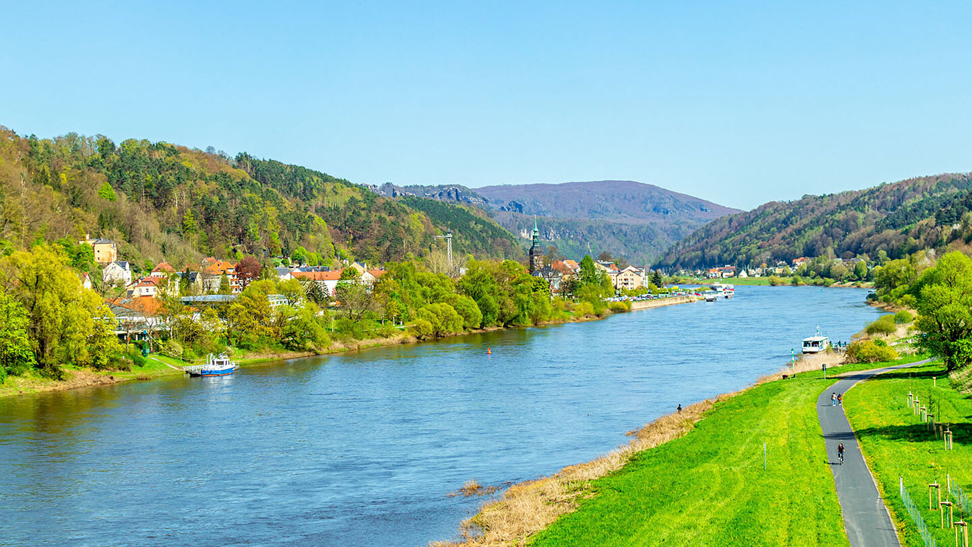 Elbe bei Dresden mit grünen Ufern, sanften Hügeln und weiter Landschaft unter blauem Himmel.