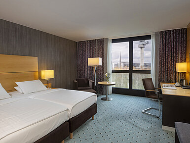 Classic Zimmer Classic Zimmer im Maritim Hotel Düsseldorf mit Doppelbett, Schreibtisch und Panoramafenster mit Blick auf die Umgebung.