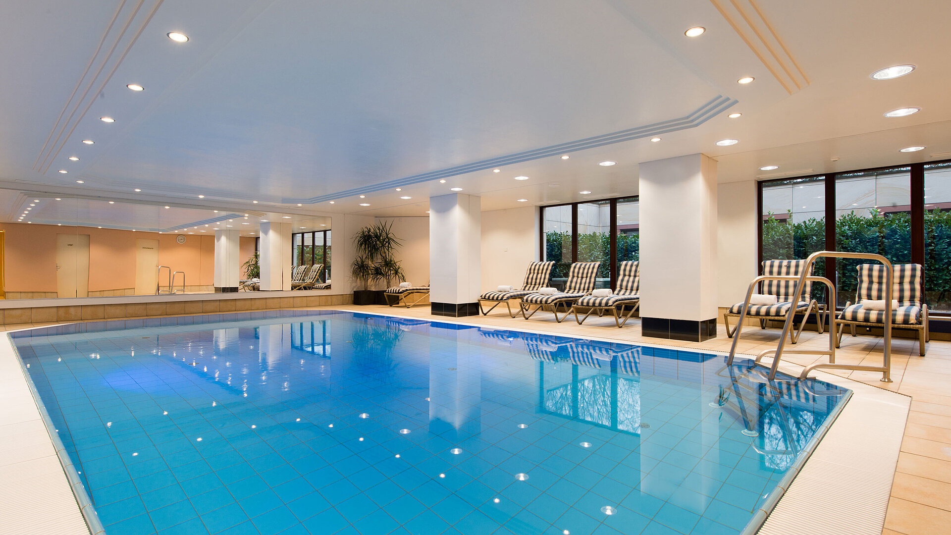 Modernes Hallenbad im Maritim Hotel Fulda mit Liegestühlen, großen Fenstern und entspannter Atmosphäre.