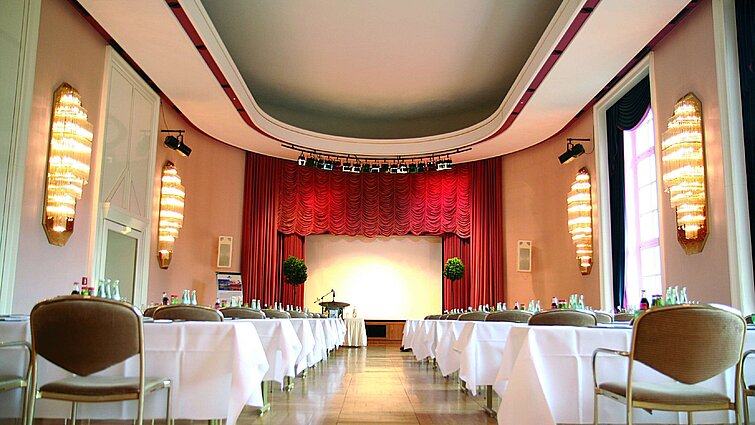 Konferenzsaal im Maritim Hotel Bad Wildungen mit Bühne, roten Vorhängen und Tageslicht
