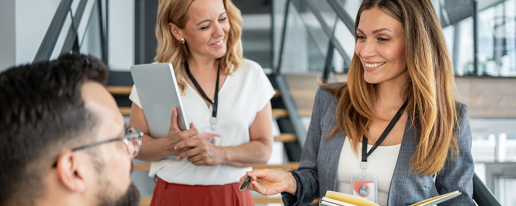 © Migma Agency - AdobeStock.com Drei Geschäftsleute mit Notizbüchern im Gespräch bei einem Networking-Event