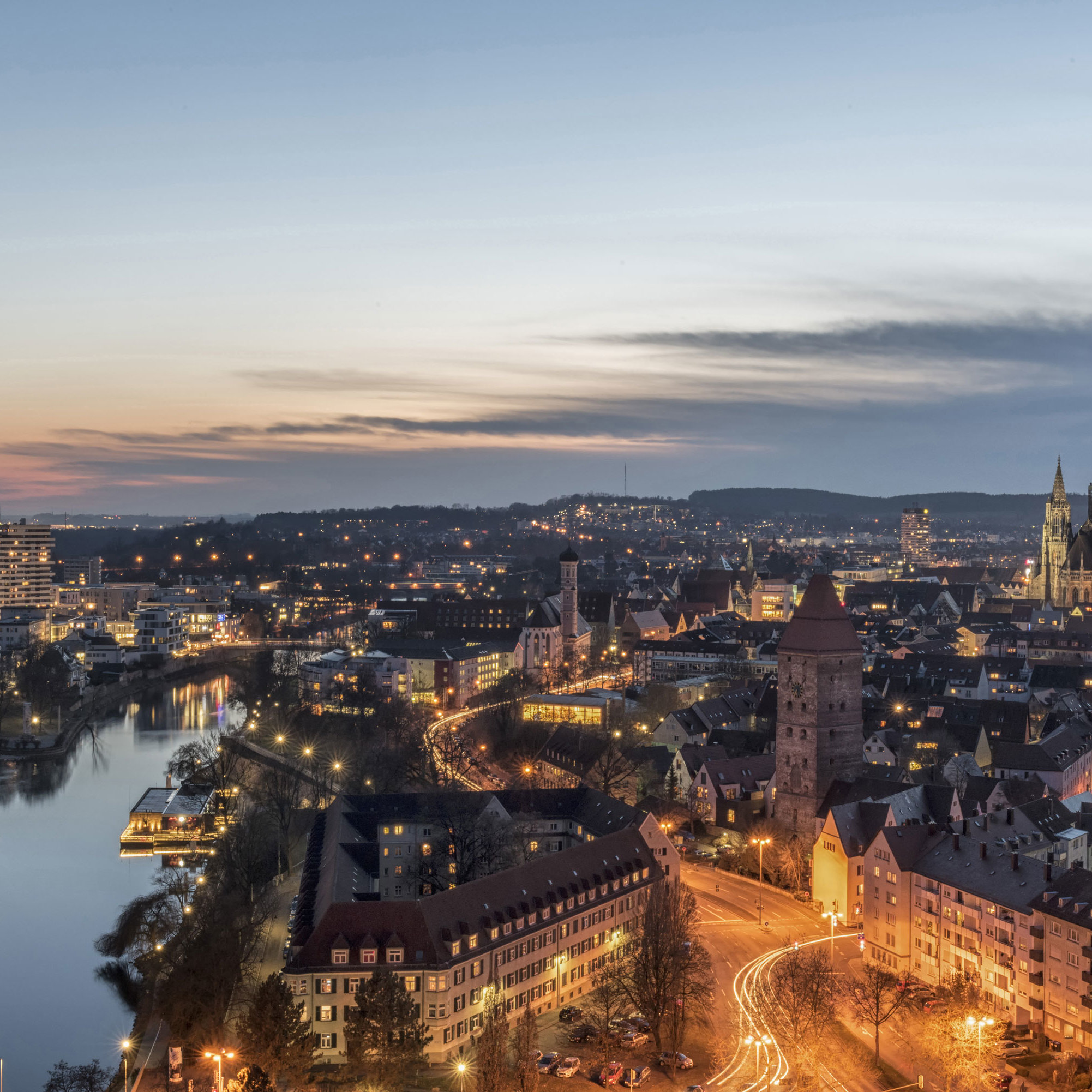 Nachtpanorama von Ulm mit beleuchtetem Münster und Donau, stimmungsvoll zur blauen Stunde.
