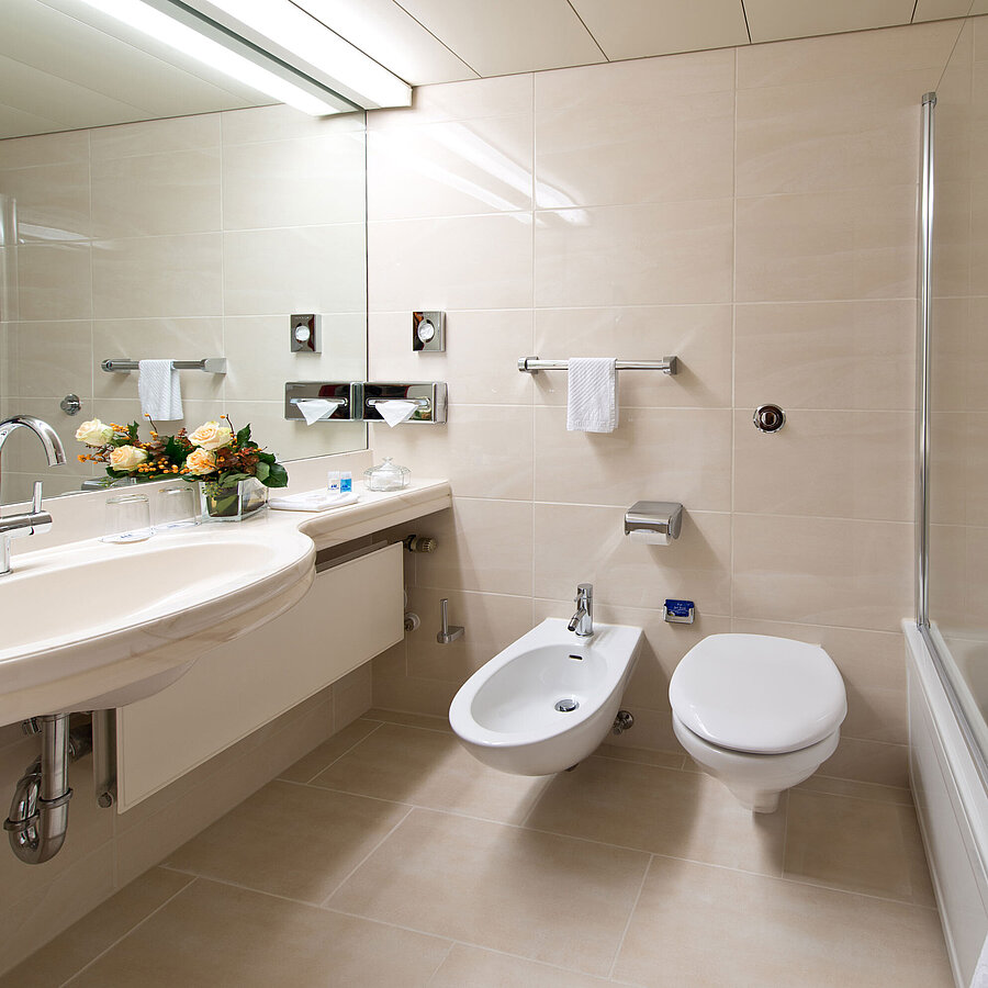 Badezimmer Helles, elegantes Badezimmer mit Badewanne, Dusche, Waschbecken und Spiegel im Maritim Hotel Hannover.