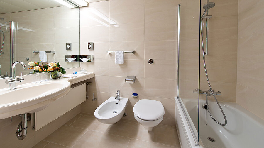 Helles, elegantes Badezimmer mit Badewanne, Dusche, Waschbecken und Spiegel im Maritim Hotel Hannover.