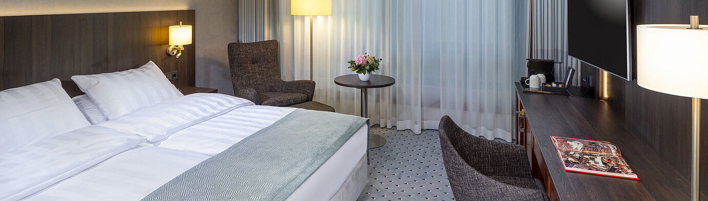 Superior Doppelzimmer Modernes Superior Doppelzimmer im Maritim Bremen mit Sitzbereich, Schreibtisch und großem Fenster für natürliche Beleuchtung.