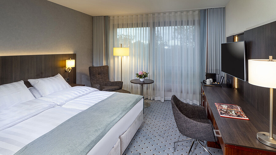 Modernes Superior Doppelzimmer im Maritim Bremen mit Sitzbereich, Schreibtisch und großem Fenster für natürliche Beleuchtung.
