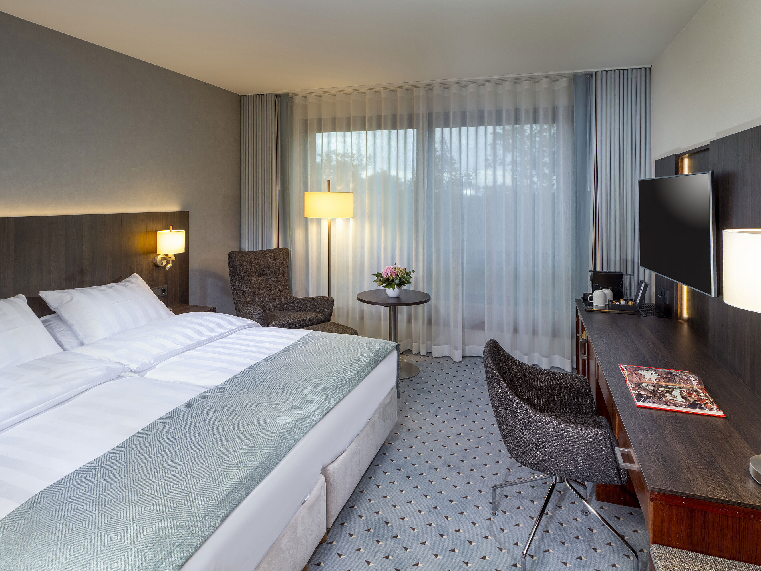 Modernes Superior Doppelzimmer im Maritim Bremen mit Sitzbereich, Schreibtisch und großem Fenster für natürliche Beleuchtung.