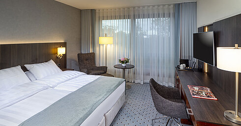 Modernes Superior Doppelzimmer im Maritim Bremen mit Sitzbereich, Schreibtisch und großem Fenster für natürliche Beleuchtung.
