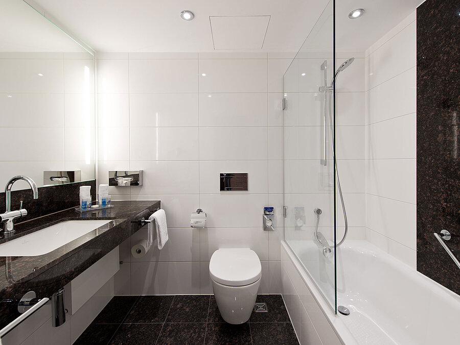 Modernes Badezimmer im Maritim Hotel Darmstadt mit eleganter Badewanne, dunkler Granit-Arbeitsplatte und heller Wandgestaltung.