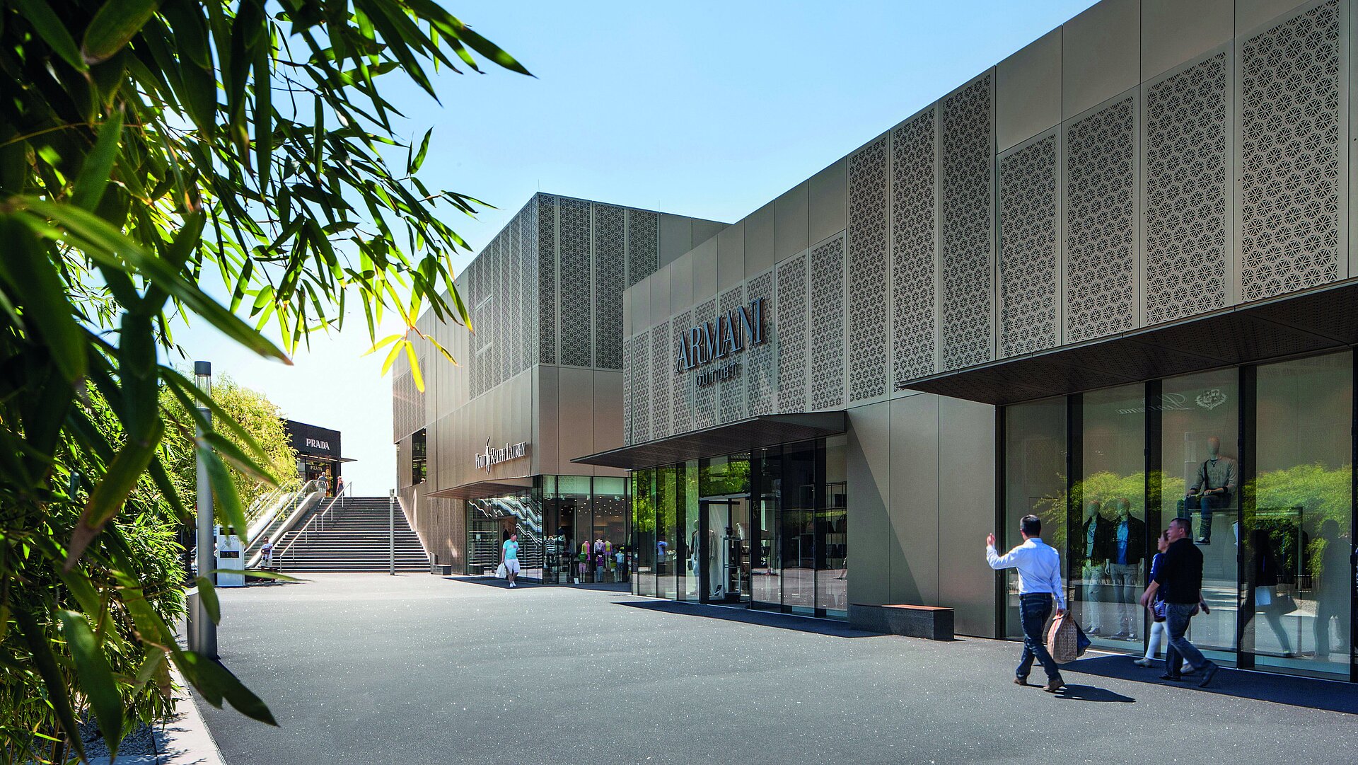 Shopping Armani Outlet Store mit moderner Fassade, Einkaufsbereich und Besuchern bei Sonnenschein