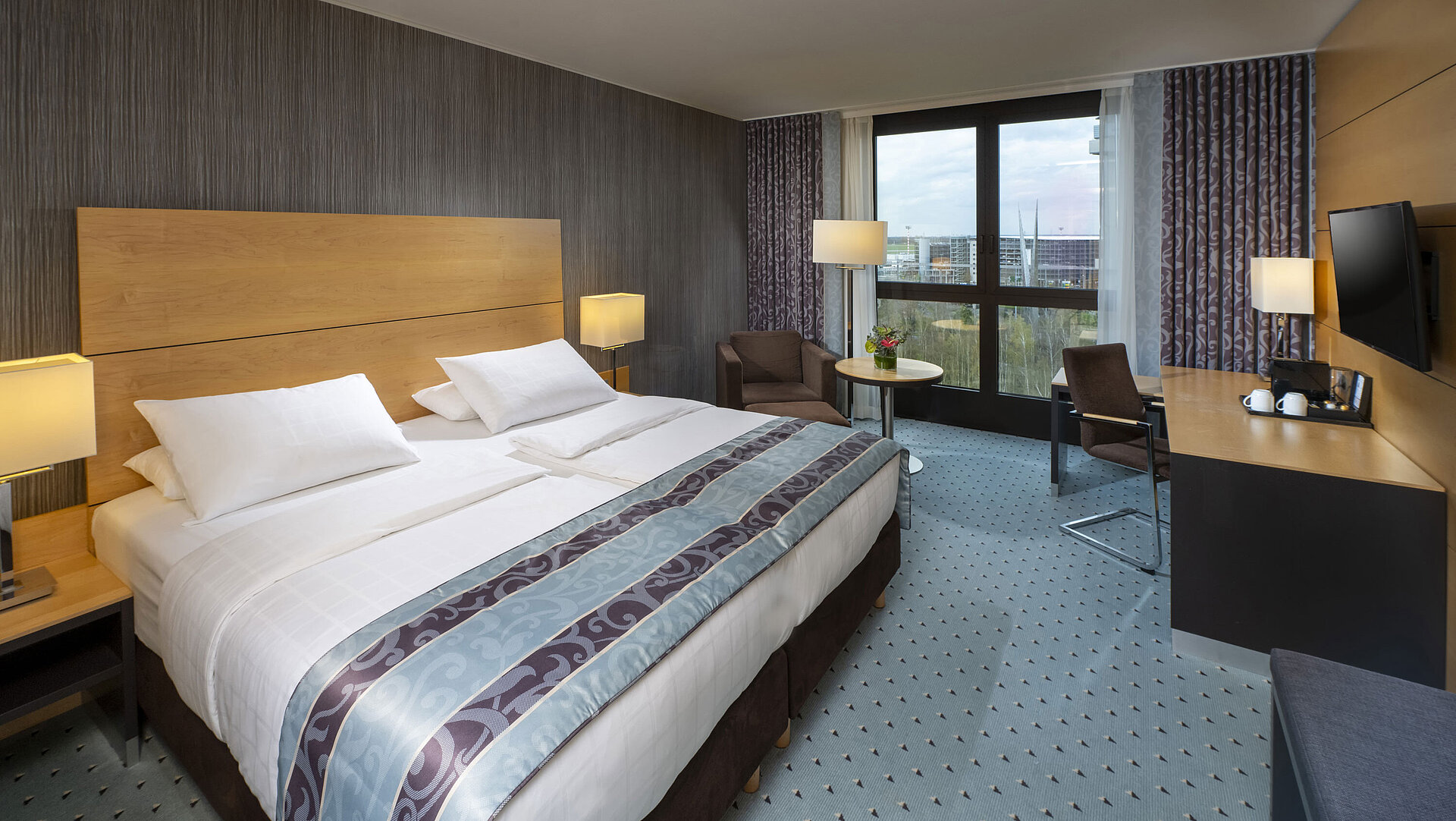 Modernes Superior-Zimmer im Maritim Hotel Düsseldorf mit großem Bett, Schreibtisch und Blick auf die Stadt.