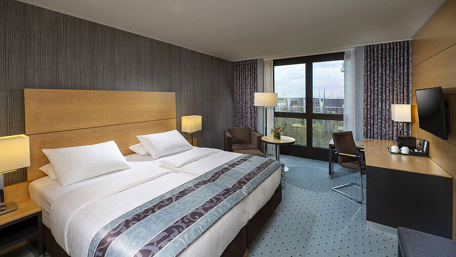 Modernes Superior-Zimmer im Maritim Hotel Düsseldorf mit großem Bett, Schreibtisch und Blick auf die Stadt.