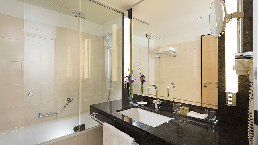 Elegantes Badezimmer im Maritim Hotel Düsseldorf mit großer Badewanne, Spiegel, Waschbecken und modernen Armaturen.