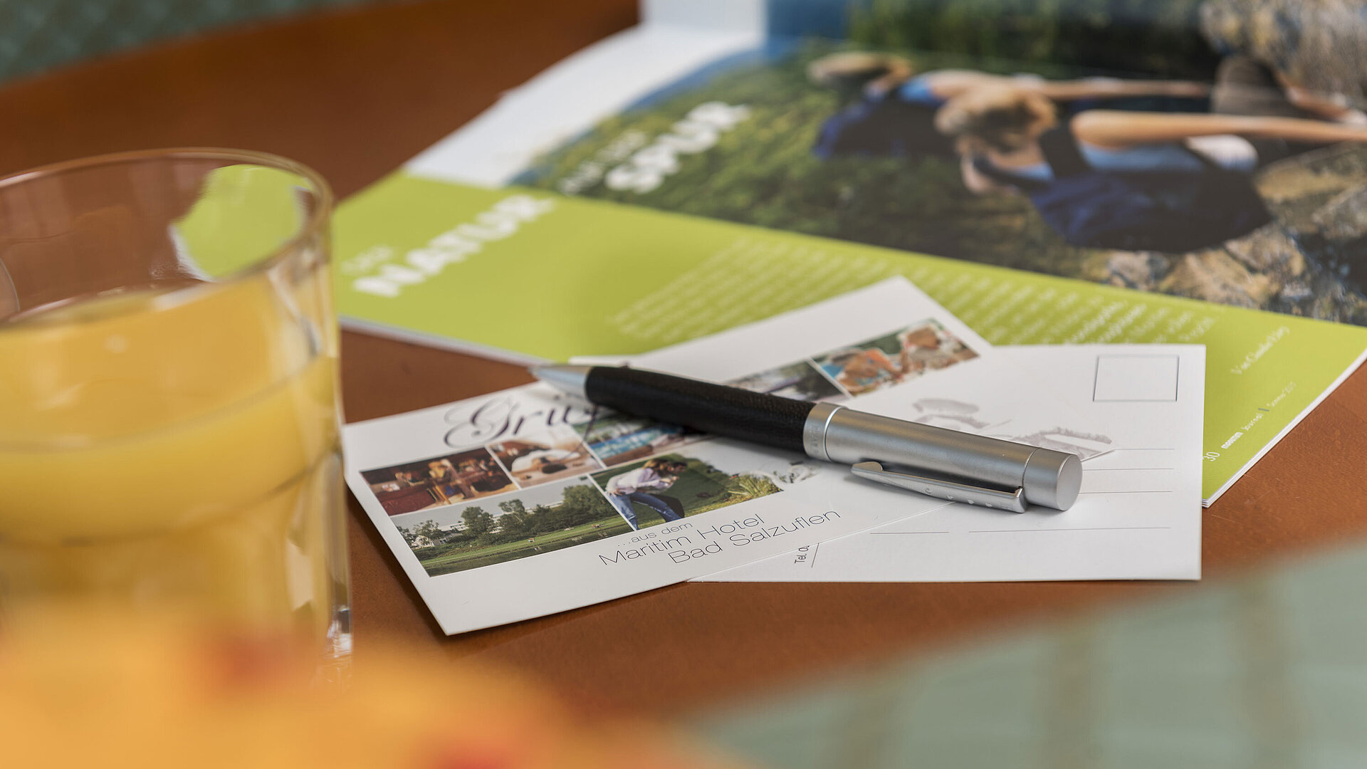 Zimmerdetail Tisch mit Postkarte vom Maritim Hotel Bad Salzuflen, Kugelschreiber, Saft und Broschüre
