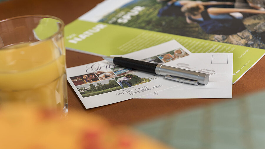 Tisch mit Postkarte vom Maritim Hotel Bad Salzuflen, Kugelschreiber, Saft und Broschüre