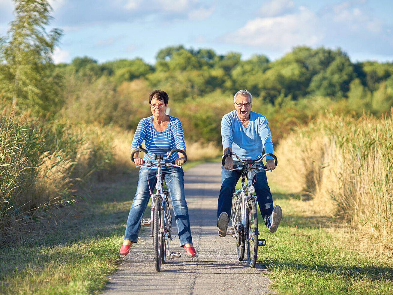 © Jenny Sturm - AdobeStock.com Paar macht eine Fahrradtour auf einem Weg durch die Natur bei sonnigem Wetter