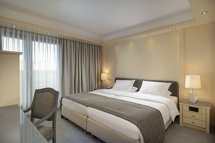 Luxuriöses Schlafzimmer in einer Suite des Maritim Hotels Darmstadt mit gemütlichem Doppelbett und klassischem Design.