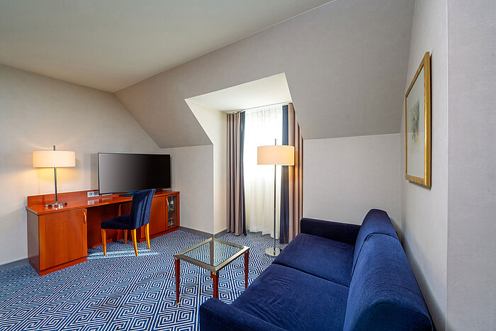 Wohnbereich im Classic Familienzimmer des Maritim Hotel Würzburg mit Schlafsofa und Schreibtisch