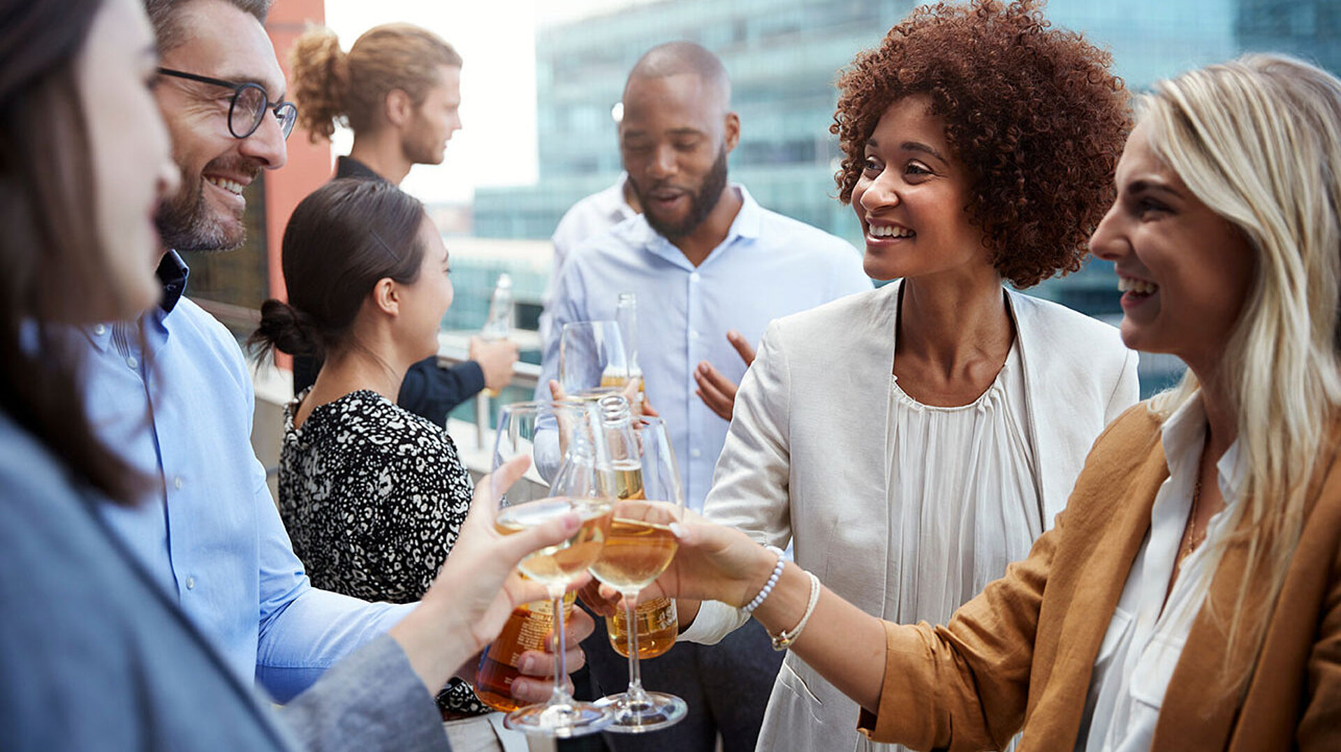 © Monkey Business - AdobeStock.com Kolleg:innen stoßen bei einem Business-Event mit Getränken an und genießen den gemeinsamen Austausch.
