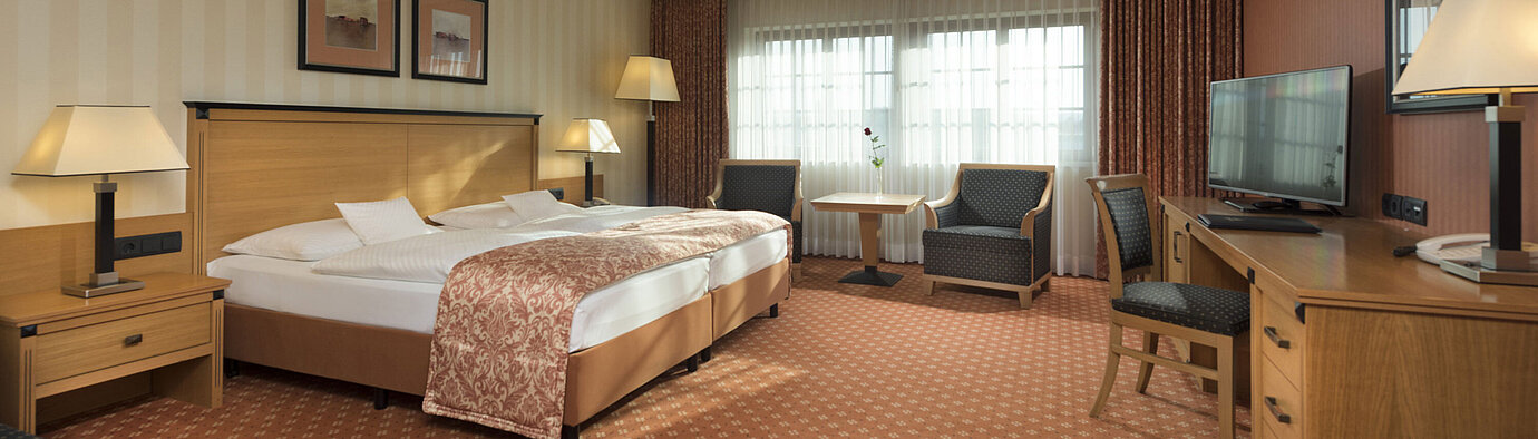 Classic Zimmer im Maritim Hotel Dresden mit Doppelbett, Sitzbereich und klassischem Dekor.