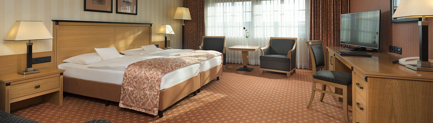 Classic Zimmer im Maritim Hotel Dresden mit Doppelbett, Sitzbereich und klassischem Dekor.