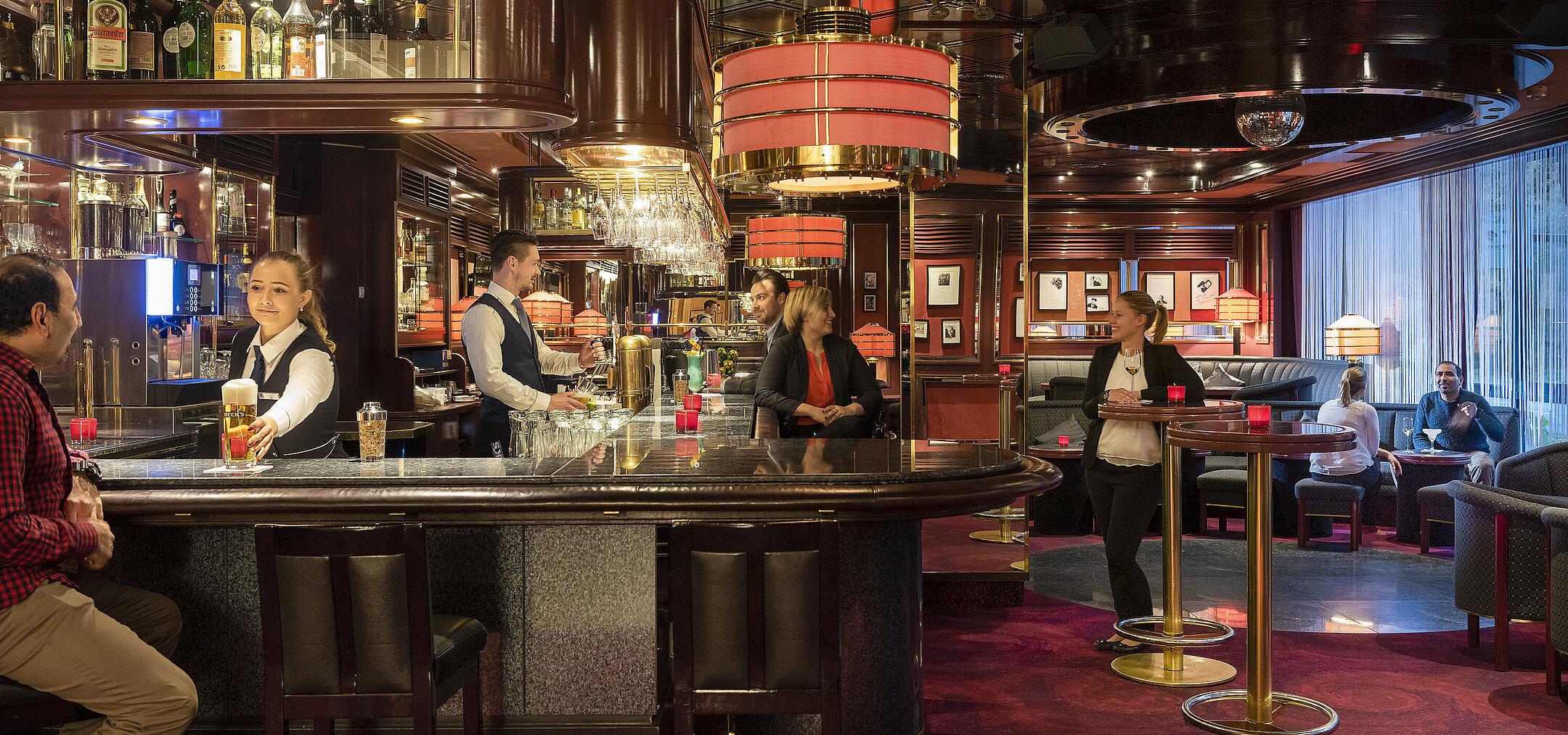 Gäste genießen Drinks und entspannte Atmosphäre in der stilvollen Bar des Maritim Bremen, bedient von freundlichem Personal.