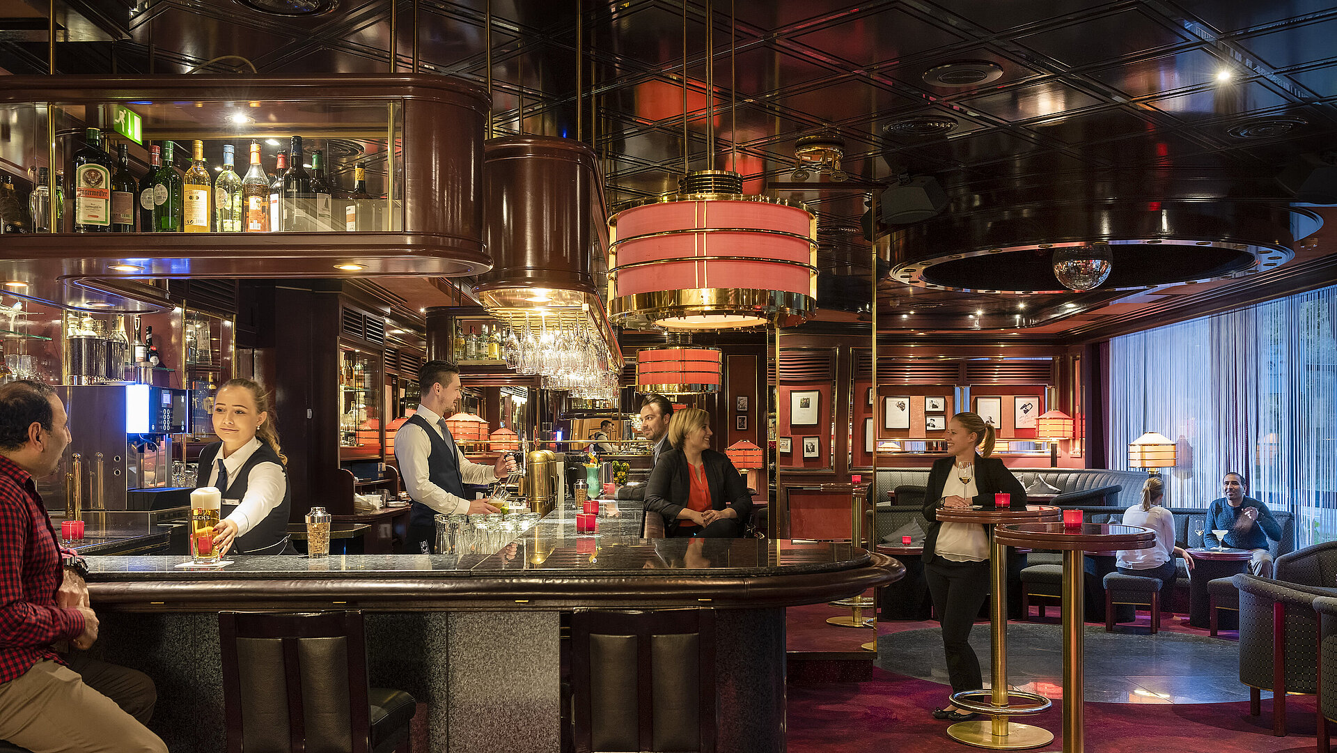 Gäste genießen Drinks und entspannte Atmosphäre in der stilvollen Bar des Maritim Bremen, bedient von freundlichem Personal.