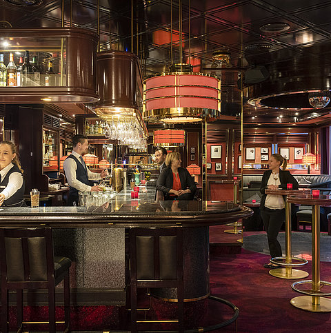Gäste genießen Drinks und entspannte Atmosphäre in der stilvollen Bar des Maritim Bremen, bedient von freundlichem Personal.