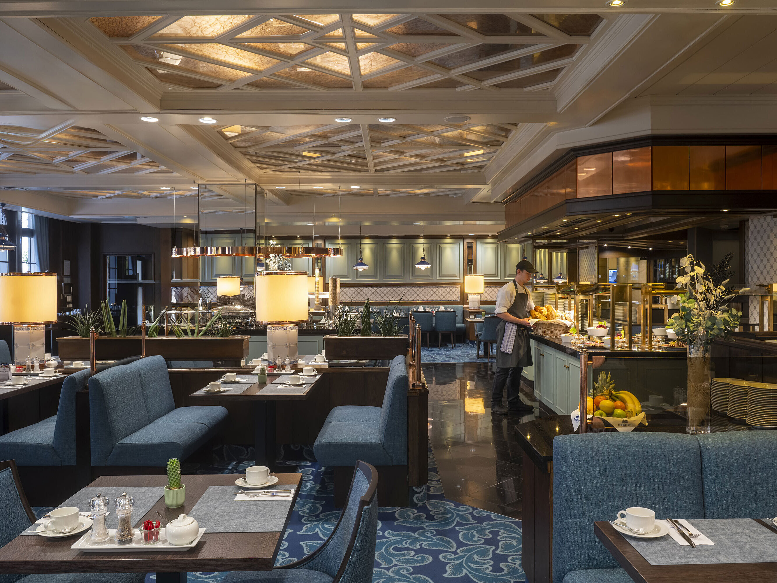 Restaurant im Maritim Hotel Darmstadt mit gedeckten Tischen, Buffetbereich und eleganter Beleuchtung unter kunstvoller Decke.