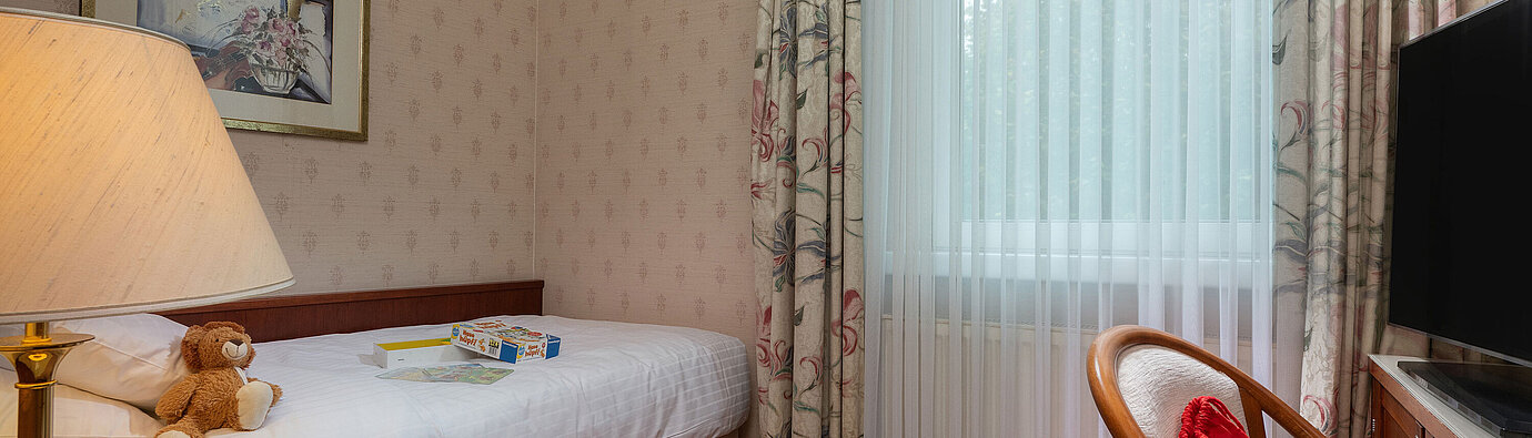 Comfort Familienzimmer mit Einzelbett, Spielzeug, Sitzbereich und großer Fensterfront für einen gemütlichen Aufenthalt.