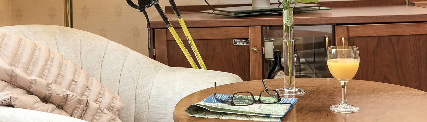 Heller Sitzbereich mit Nordic-Walking-Stöcken, Rose, TV und Getränk im Maritim Hotel Bad Wildungen