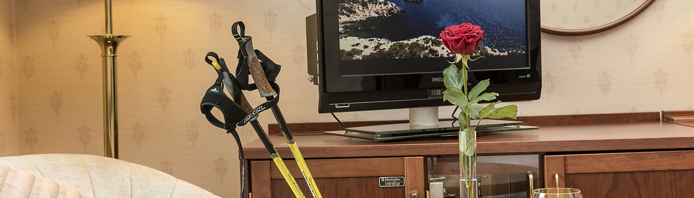 Heller Sitzbereich mit Nordic-Walking-Stöcken, Rose, TV und Getränk im Maritim Hotel Bad Wildungen