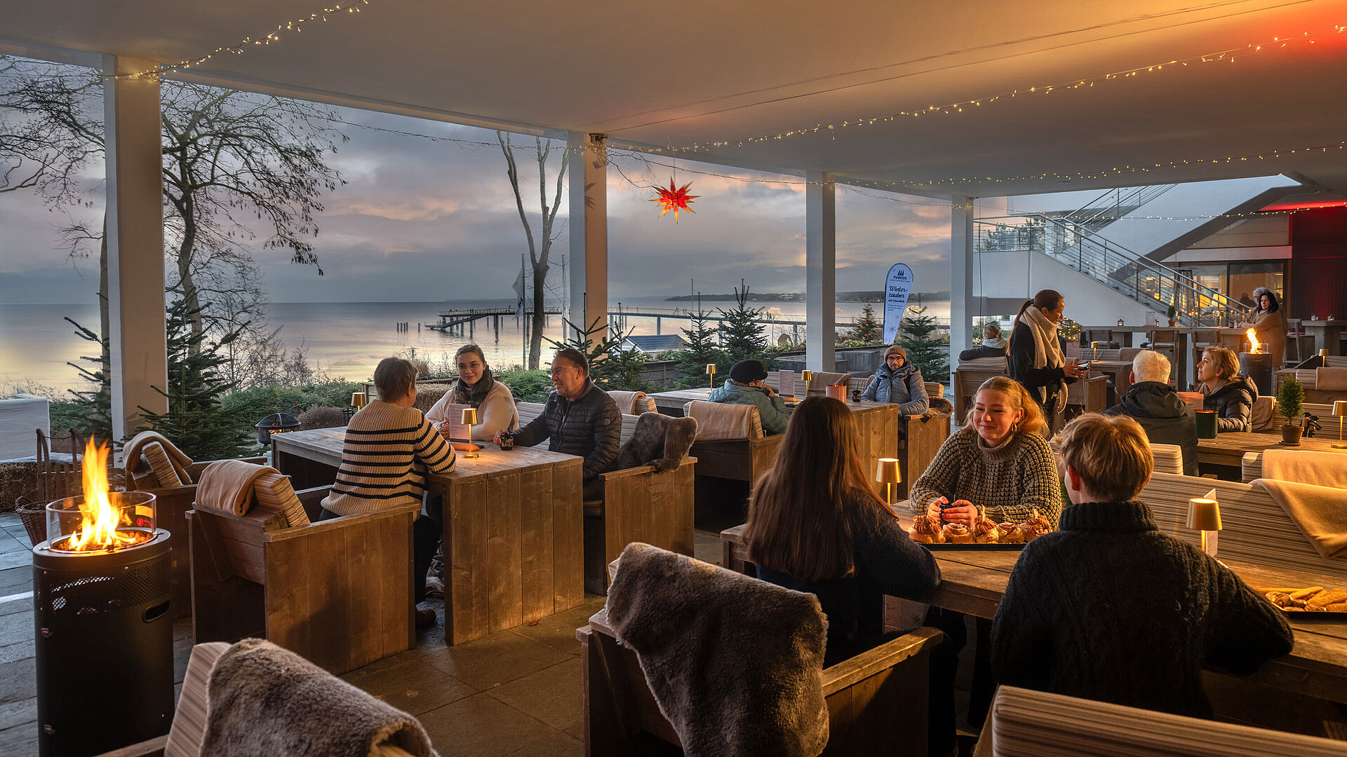 Winterzauber an der Ostsee Festlich dekorierter Terrassenbereich mit Kerzenlicht, Winterdekoration und Blick auf die Ostsee.