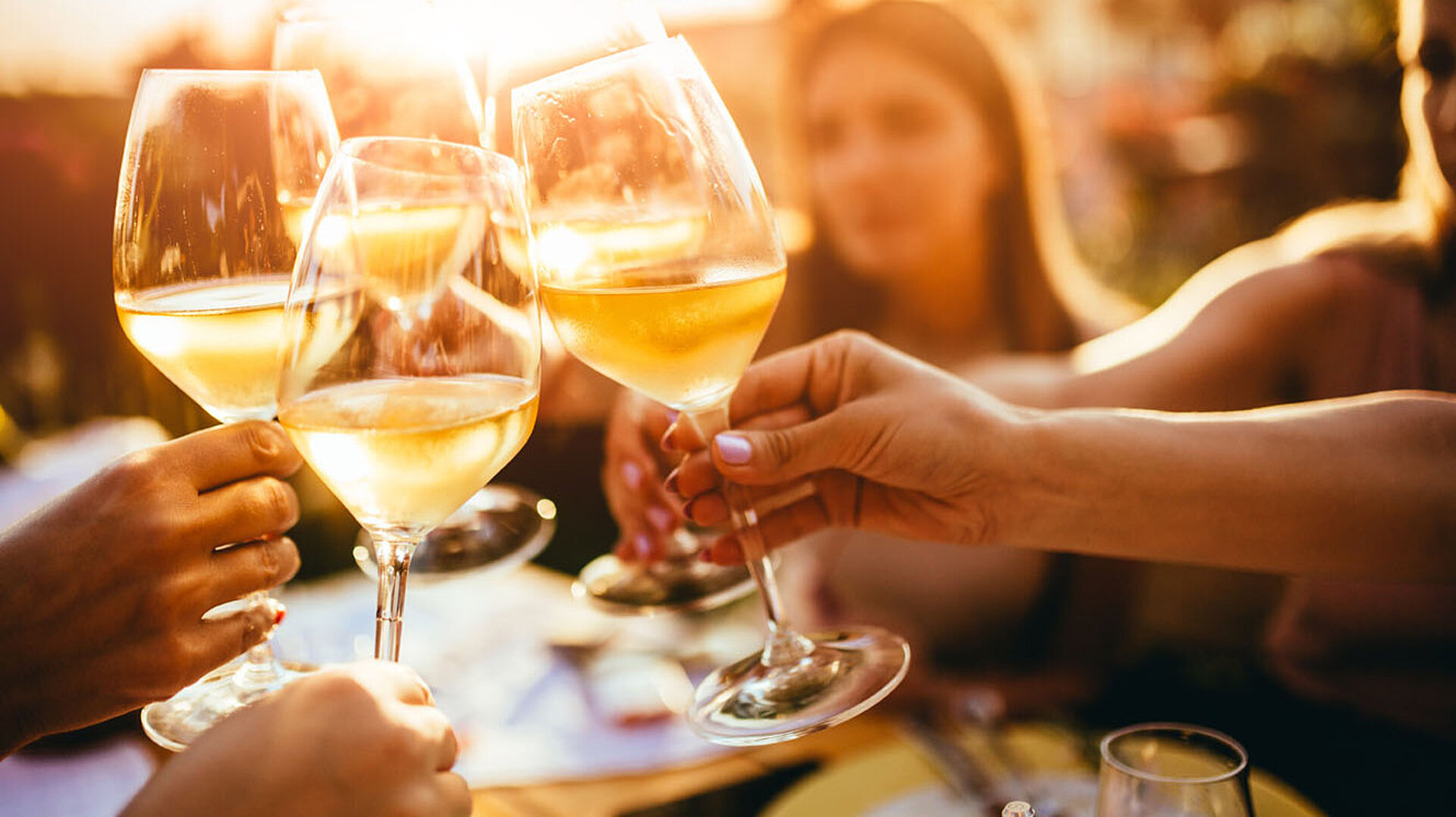 ©minastefanovic - AdobeStock.com Freunde stoßen mit Weingläsern an und genießen einen gemeinsamen Abend bei Sonnenuntergang