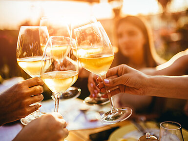 Freunde stoßen mit Weingläsern an und genießen einen gemeinsamen Abend bei Sonnenuntergang